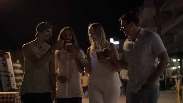 Friends toasting with coffee cups in night street