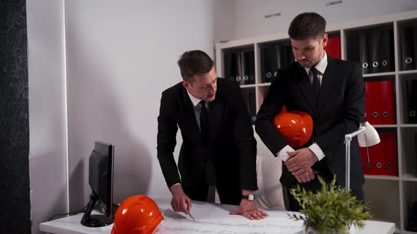 Two Engineers Businessmen Look at Architect Drawing with Helmet