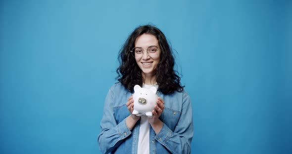 A Happy Young Girl Holds a Cute Piggy Bank Money Box