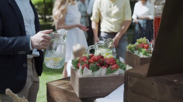 Male Hand Pours Lemonade Into a Glass on Catering Outside