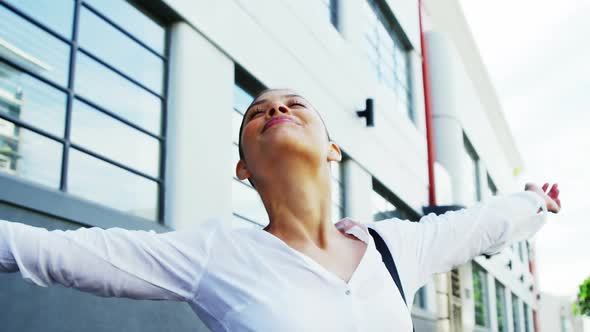 Woman outdoors raising arms in joy with building background