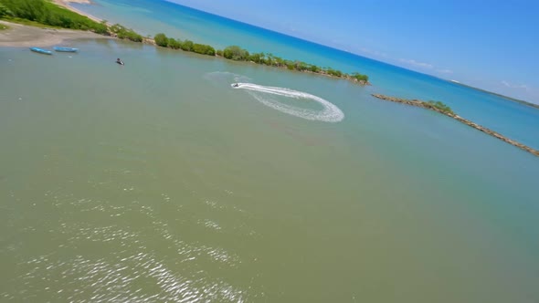 Aerial drone fpv flying around jet ski over Caribbean sea waters at Playa Nueva Romana beach, San Pe