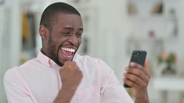 Portrait of African Man Celebrating Success on Smartphone 