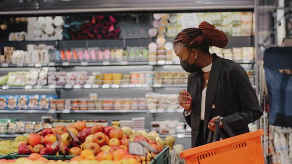 African American Young Woman in Medical Mask Choosing Apple Fruit Vegetable in Supermarket