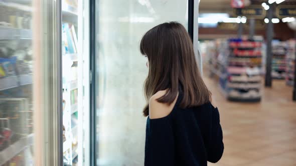Independent Teenager in the Supermarket Opens Freezer Door and Take an Ice Cream
