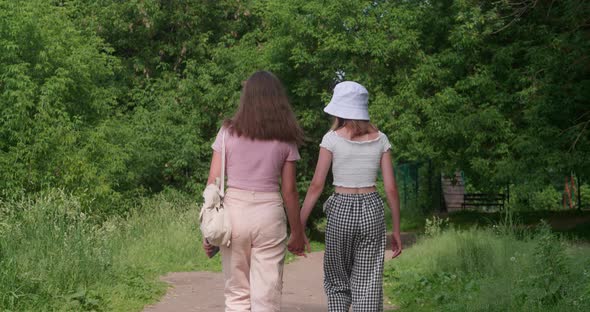 Young Girls Holding Hands and Looking Back at Camera Outdoors