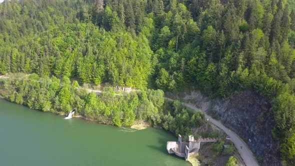 Aerial Downwards shot of road next to lake/reservoir with trees next to water front