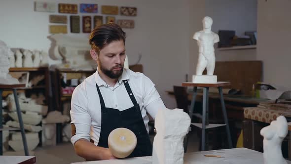 Young Master Working with Hammer, Chisel and Limestone Under Creation Future Sculpture