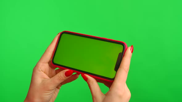 Female Hand Holds Mobile Phone with Workspace Mock Up Screen on Green Background in Horizontal