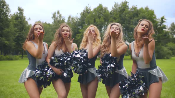 Girls Cheerleaders with Pompons Blowing Kisses Smiling at Camera