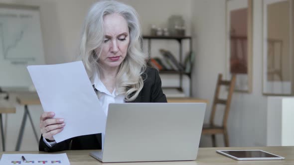 Old Businesswoman Working on Documents and Laptop