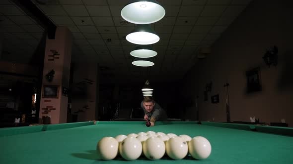 A Young Man Playing Billiards in a Club in the Evening