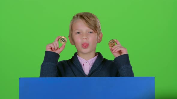 Teen Emerges From Behind the Board with Two Chips and Shows Tongue on a Green Screen