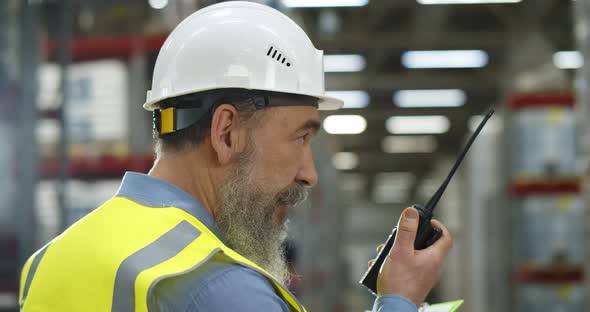 Close Up of Aged Manager Using Walkietalkie in Warehouse