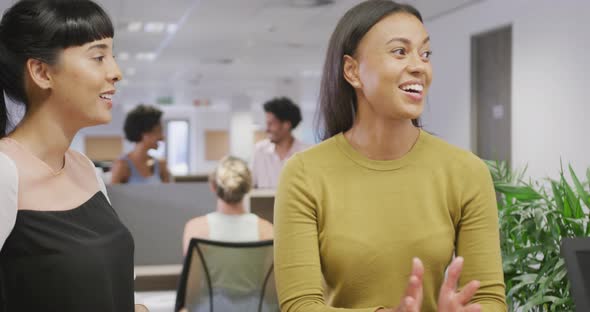 Diverse female business colleagues talking and smiling in office