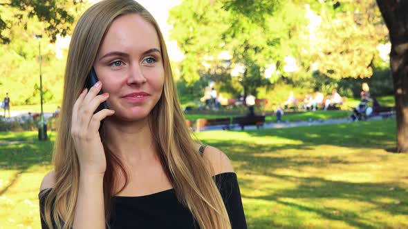 Young Beautiful Woman Phone in the Park in Sunny Day