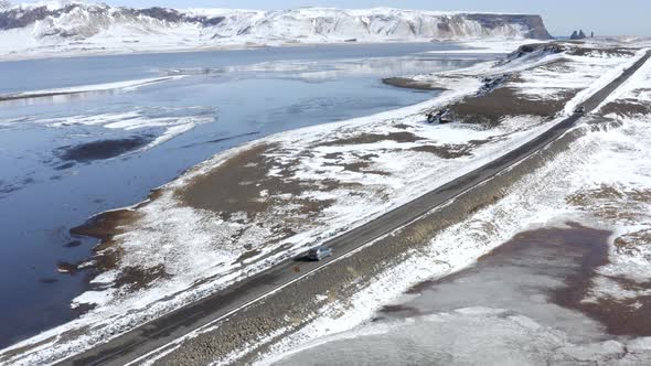 Cars Driving Along a Snowy Road With a Lake Surrounding