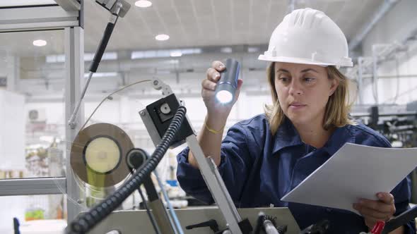 Serious Female Factory Worker Checking Equipment Specifications