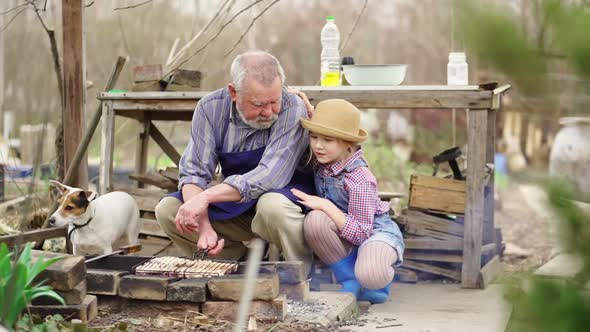 Granddaughter Helps Grandfather Cook Barbecue