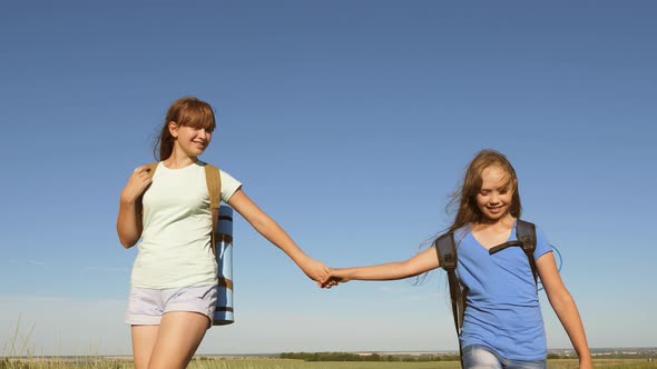 Girls, Women Travelers Go Holding Hands on a Background of Blue Sky. Close-up. Teamwork Tourists