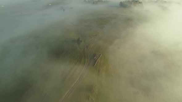 Misty morning above scenic rural Poland with green grassland, aerial