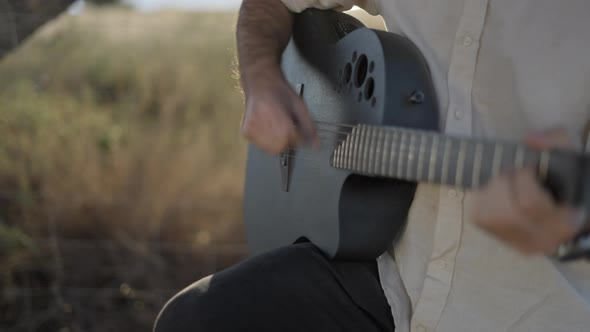 CloseUp Of Man's Hands Playing Guitar Outdoors at Sunset