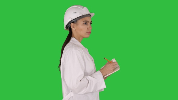 Woman engineer with helmet is holding pen and checklist