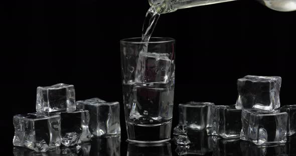 Pouring Up Shot of Vodka From a Bottle Into Glass Black Background