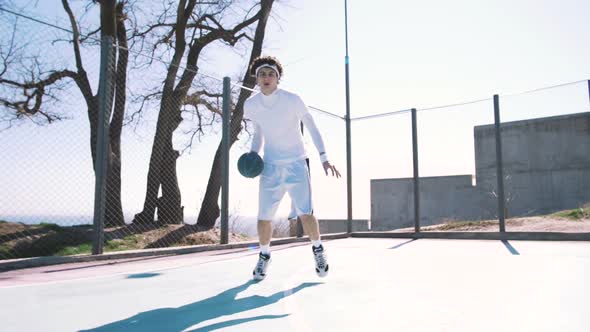 Portrait of a Basketball Player Dribbling the Ball with Skill on an Outdoor Basketball Court