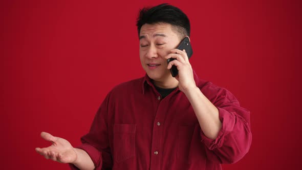 Positive Asian man wearing shirt talking by phone