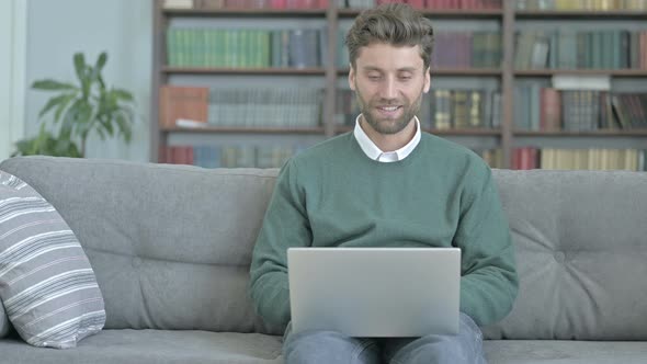 Man Sitting on Sofa and Video Calling Through Laptop