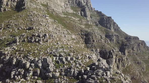 medium wide drone view of Table Mountain rock formation in late afternoon sun against blue sky with