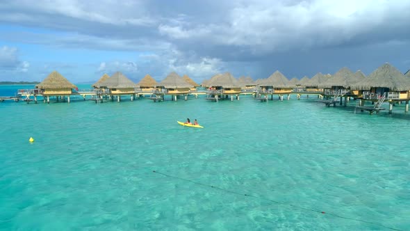 Aerial drone view of a man and woman couple on a tandem sea kayak in Bora Bora tropical island.