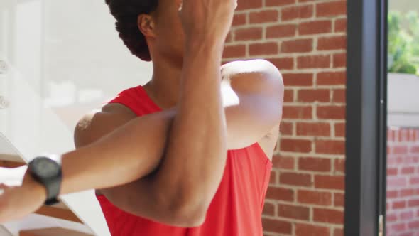 Fit african american man exercising at home and doing stretching at home