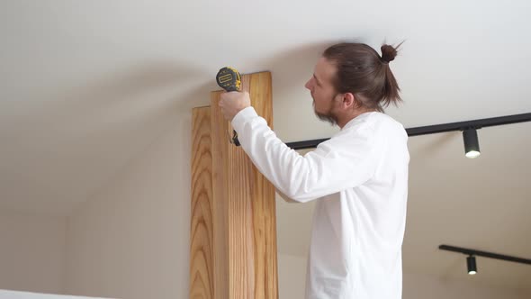 the Carpenter Screws with a Screwdriver Wooden Ash Lamellae to the Ceiling