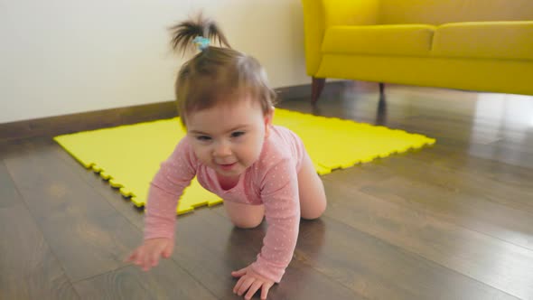 Cinematic Shot of a Cute Happy Little Toddler Baby Boy is Crawling on a Wooden Floor at Home