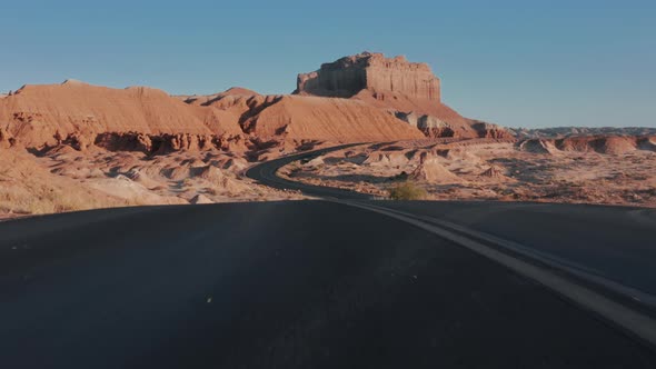 Drone Flying Low Above Scenic Black Winding Asphalt Road in Cinematic Red Desert