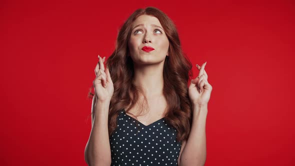 Cute Young Girl with Red Hairstyle Praying Over Studio Background