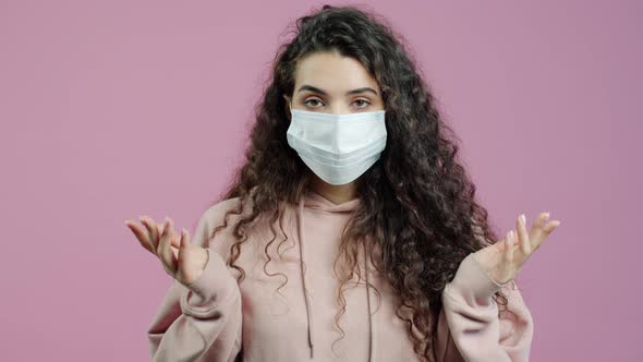 Portrait of Unhappy Young Woman Wearing Face Mask Gesturing During Covid19 Pandemic