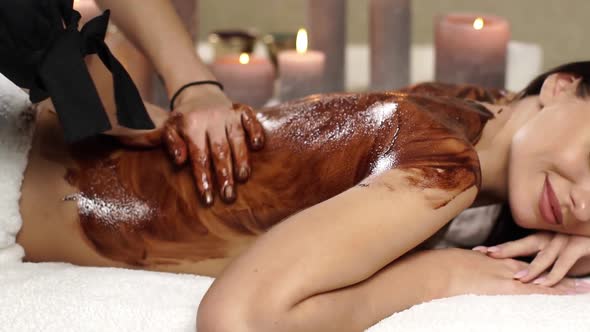 Pretty Woman Receiving Massage with Chocolate on Her Back at Spa Salon