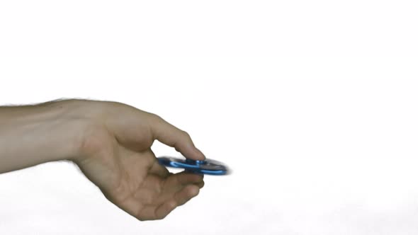 Playing with a fast blue fidget spinner in a turning hand.