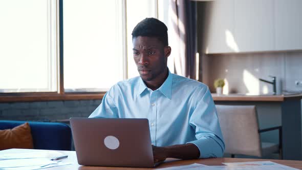 Young serious man in shirt working at computer