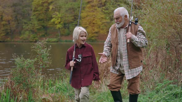Grandfather and Grandson with Fishing Rod Walking Near River