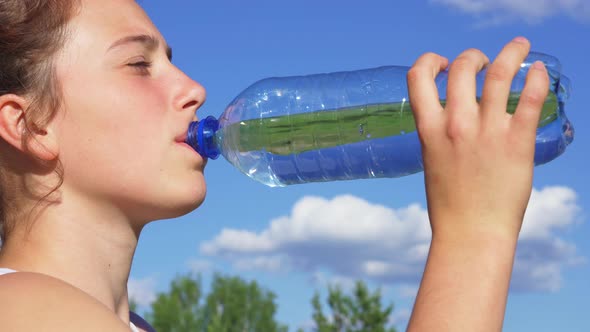 Sporty Woman Drinking Water Outdoor on Sunny Day