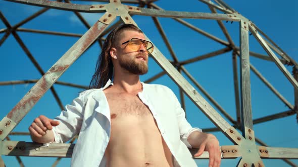 Fashion Macho Man Having Trendy Hairstyle Wearing Sunglasses Posing at Grid Background