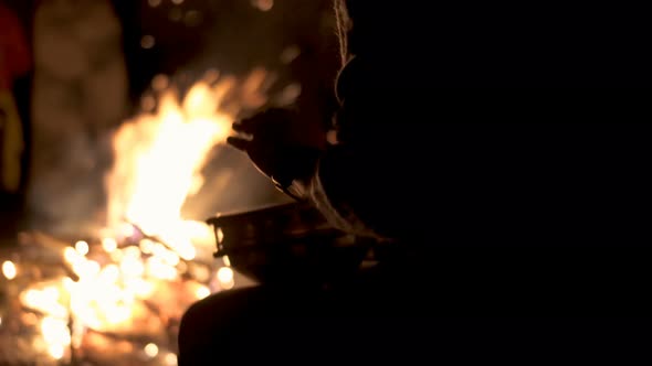 Silhouette of Drummer Playing with Hands on Percussion Drum by Campfire