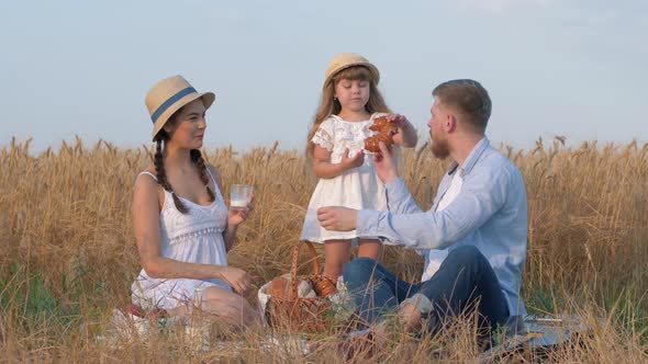 Happy Family Portrait, Young Father Bites Sweet Bun From His Daughter Hands and Smiles To Woman