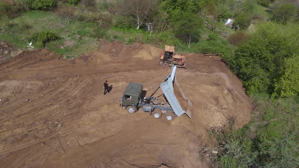 Aerial shot of tipper unloading ground on further construction site.