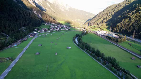 Aerial View of an Austrian Village in a Green Mountain Valley at Sunset Alps