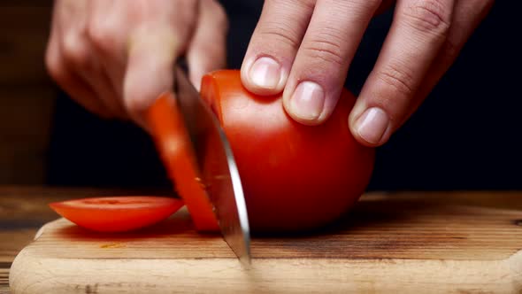 Chef's Hands Cut Fresh Tomato with a Knife on a Wooden Board